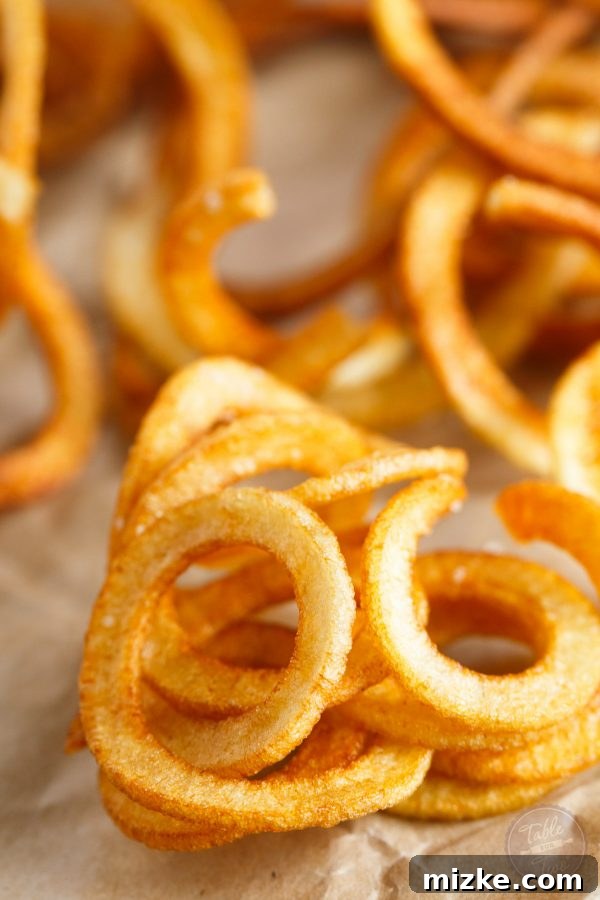 Long, raw strands of spiralized potato, illustrating the unique shape before frying.
