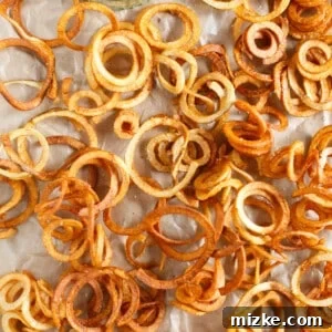 A delicious plate of homemade curly fries with a vibrant horseradish mustard dipping sauce, set against a rustic background.