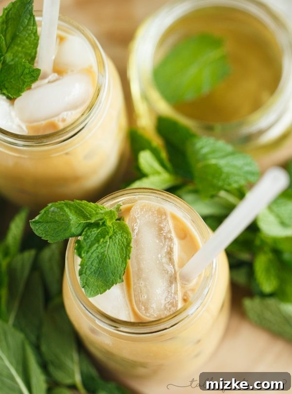 Mint Chill Latte 3 A hand pouring milk into a glass filled with ice, espresso, and mint syrup, illustrating the creation of a refreshing Iced Mint Latte.