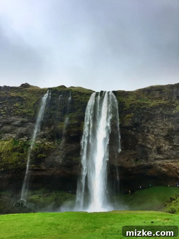 Five Days in Iceland The Vík Experience 3 Rainy and cloudy view of Seljalandsfoss waterfall in Iceland, showing people walking behind the powerful cascade