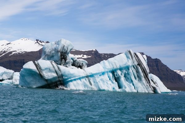 Iceland's Glacial Jewel: A 5-Day Jökulsárlón Exploration 15 A small zodiac boat dwarfed by a massive iceberg, showcasing its immense scale