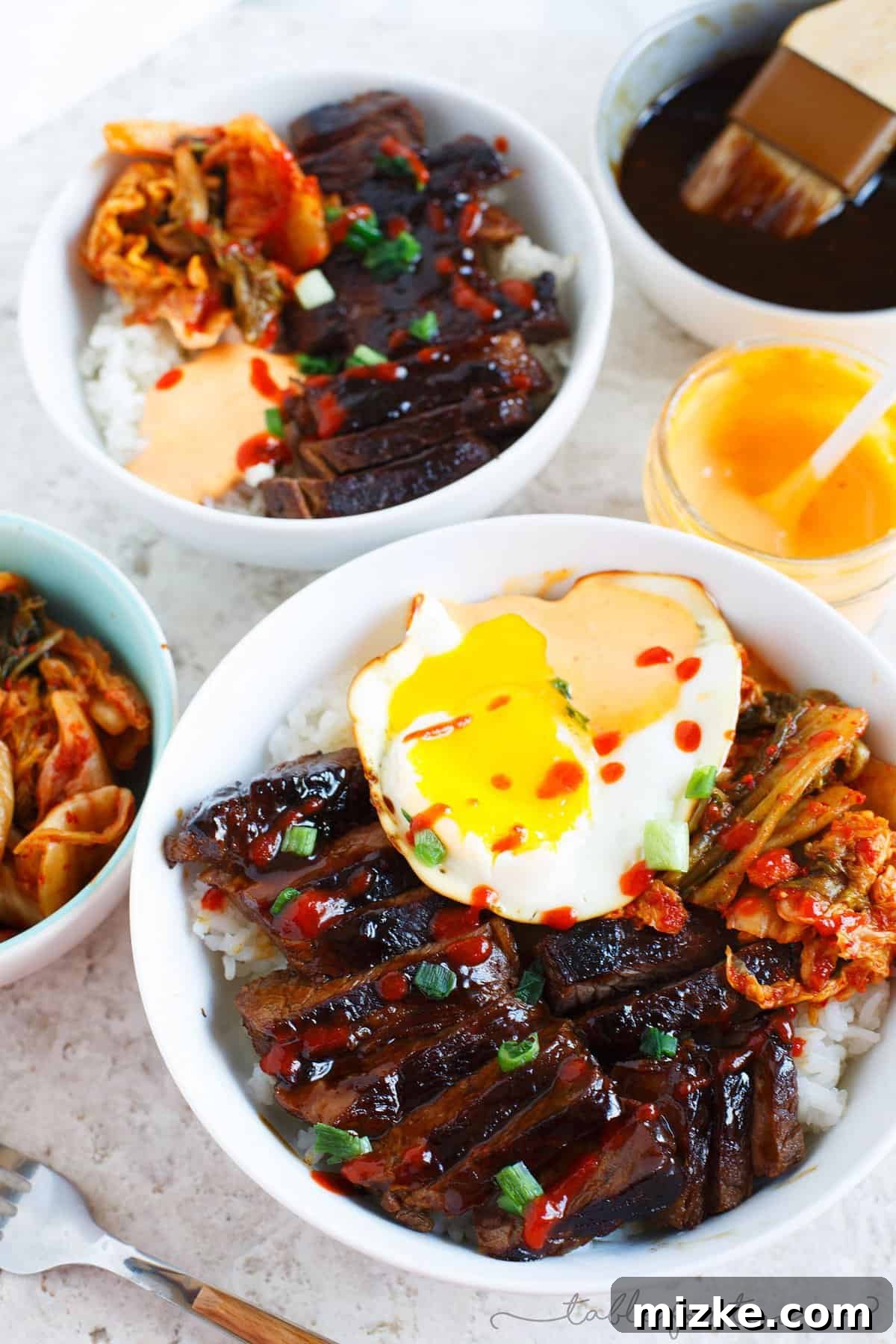 Irresistible Korean Galbi Bowls 2 Beautifully plated Korean Galbi Bowl with tender marinated beef, rice, and various vibrant toppings.