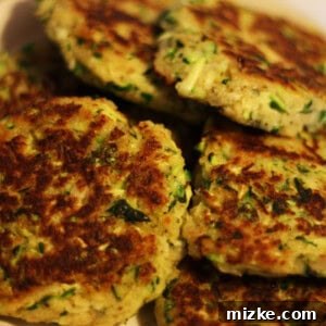 Closeup of freshly fried zucchini cakes on a white plate, ready to be served.