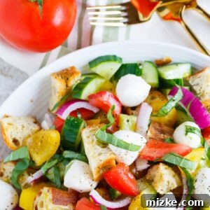 Summer Panzanella salad with toasted focaccia, colorful tomatoes, fresh basil, and mozzarella, ready to be served.