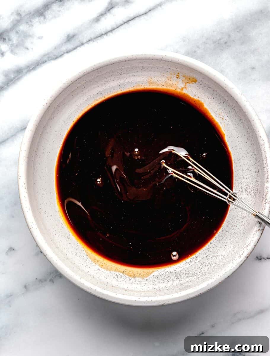 A small ceramic bowl with the mixed Pad See Ew sauce and a whisk, ready for cooking.