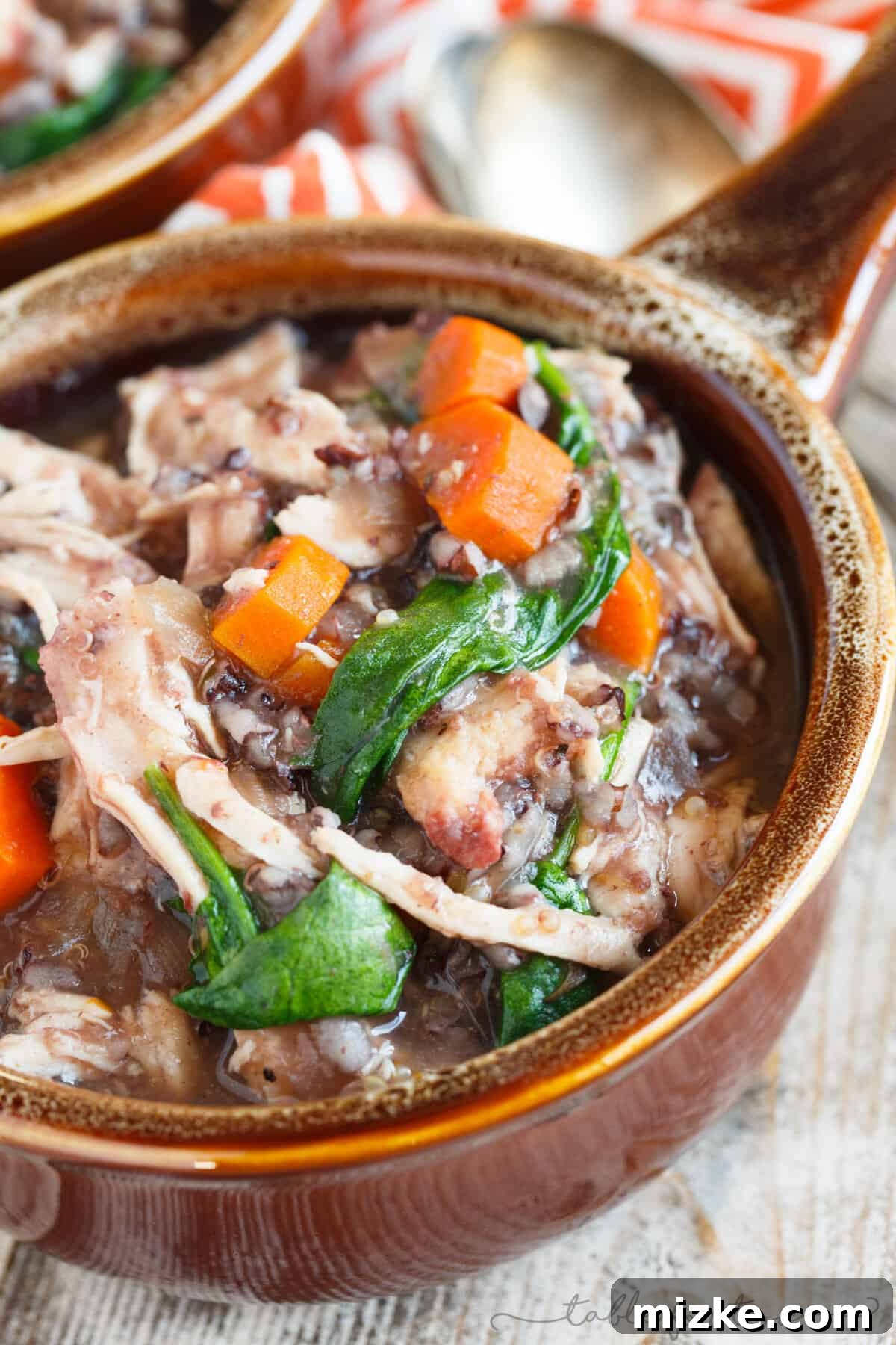 Hearty Slow Cooker Leftover Turkey Wild Rice Stew 4 A serving of slow cooker turkey and wild rice stew in a white bowl, highlighting the combination of grains, vegetables, and shredded turkey.