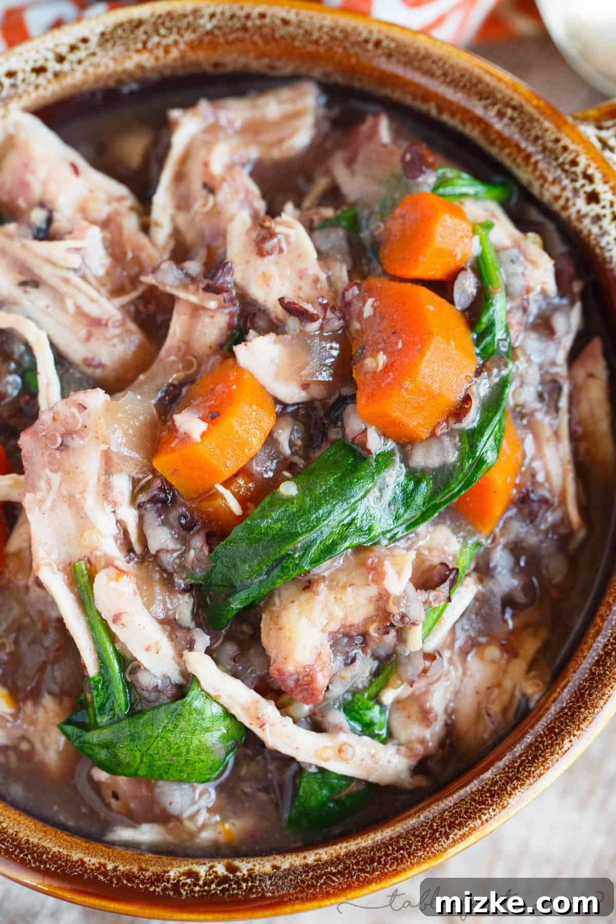 Hearty Slow Cooker Leftover Turkey Wild Rice Stew 5 Overhead shot of the slow cooker stew, showing the vibrant colors of carrots, spinach, and the rich texture of wild rice and turkey, ready to be served.
