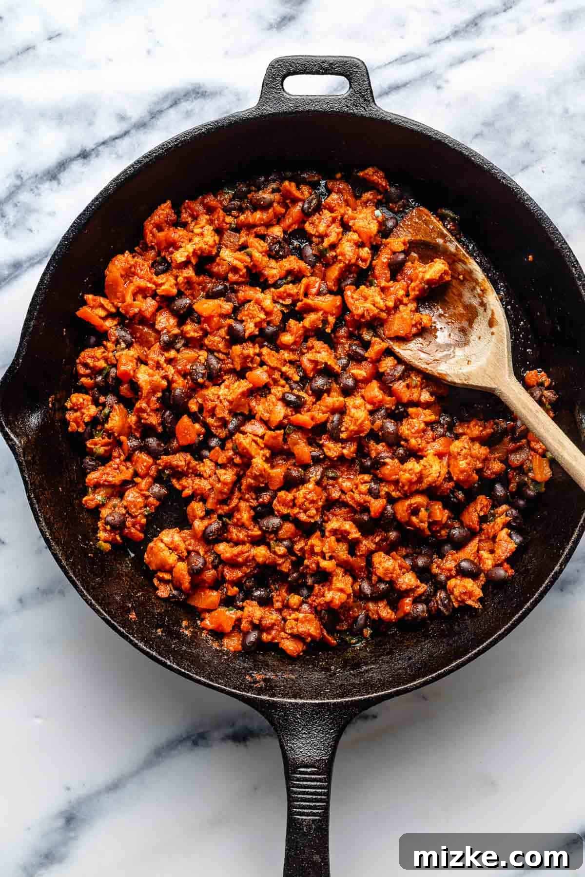 Easy to make and a bit too easy to eat, chili cheese dip is creamy, cheesy, and just the right amount of spicy from the chorizo and jalapeno. Stirring beans, tomato paste, diced tomatoes, and jalapeno into browned chorizo in a skillet.