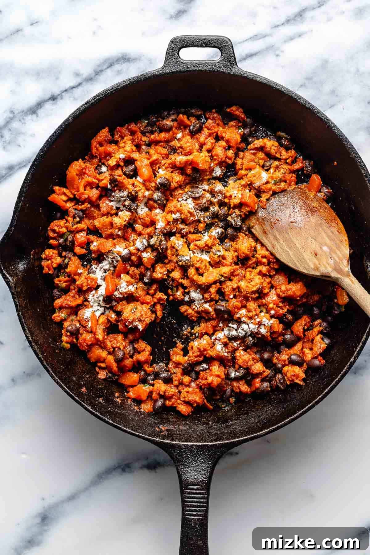 Easy to make and a bit too easy to eat, chili cheese dip is creamy, cheesy, and just the right amount of spicy from the chorizo and jalapeno. Stirring flour into a skillet full of browned chorizo, beans, tomato paste, diced tomatoes, and jalapeno.