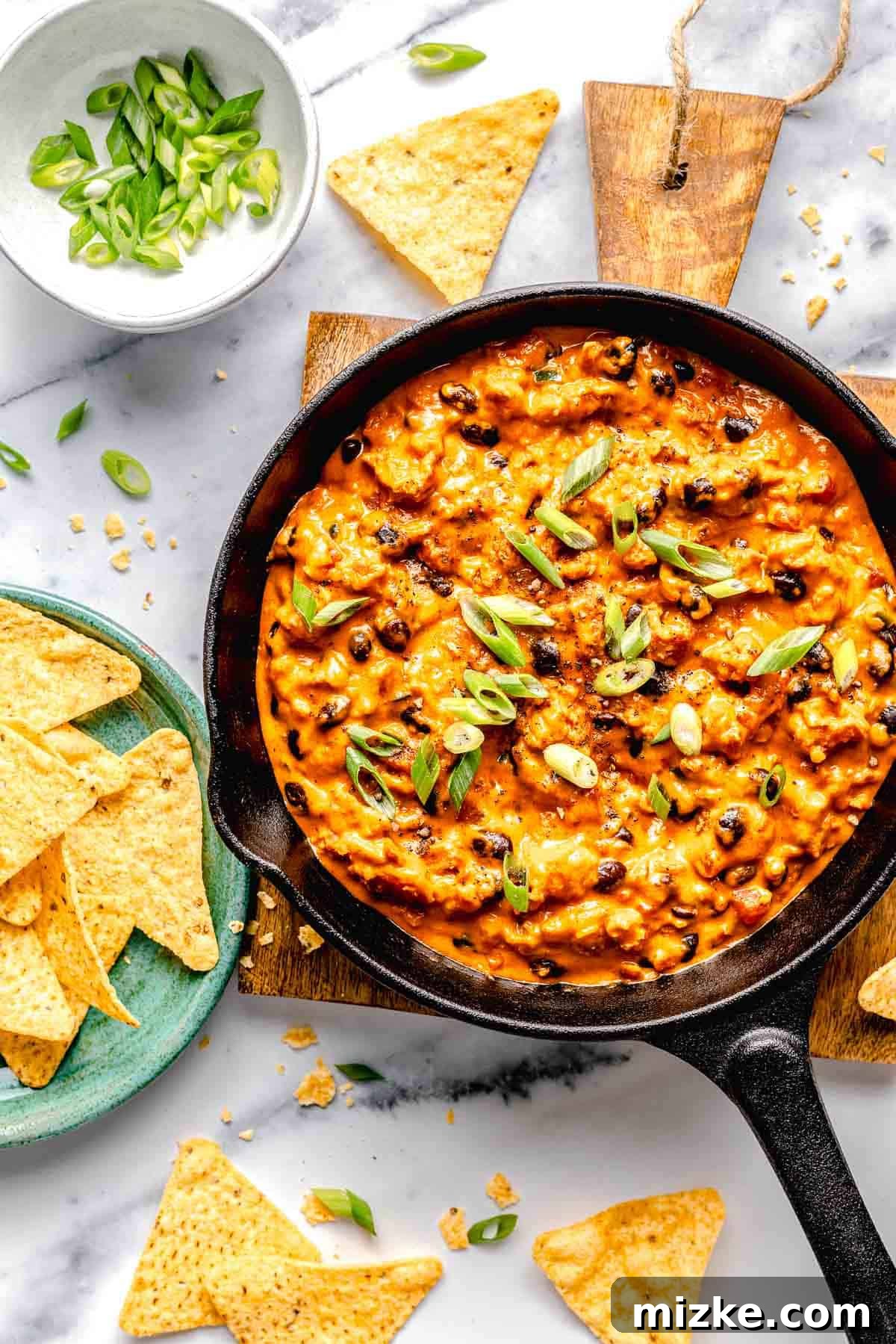 Easy to make and a bit too easy to eat, chili cheese dip is creamy, cheesy, and just the right amount of spicy from the chorizo and jalapeno. Overhead image of chili cheese dip in a skillet surrounded by tortilla chips.