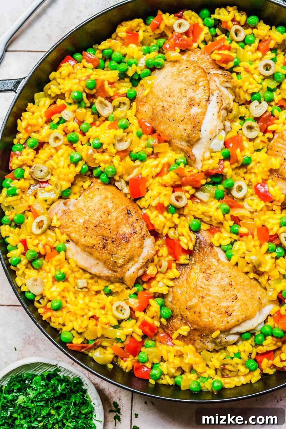 A vibrant skillet of Arroz con Pollo, ready to serve. The finished Arroz con Pollo in a large skillet, ready for serving, showing a harmonious blend of golden rice, tender chicken, and colorful vegetables.