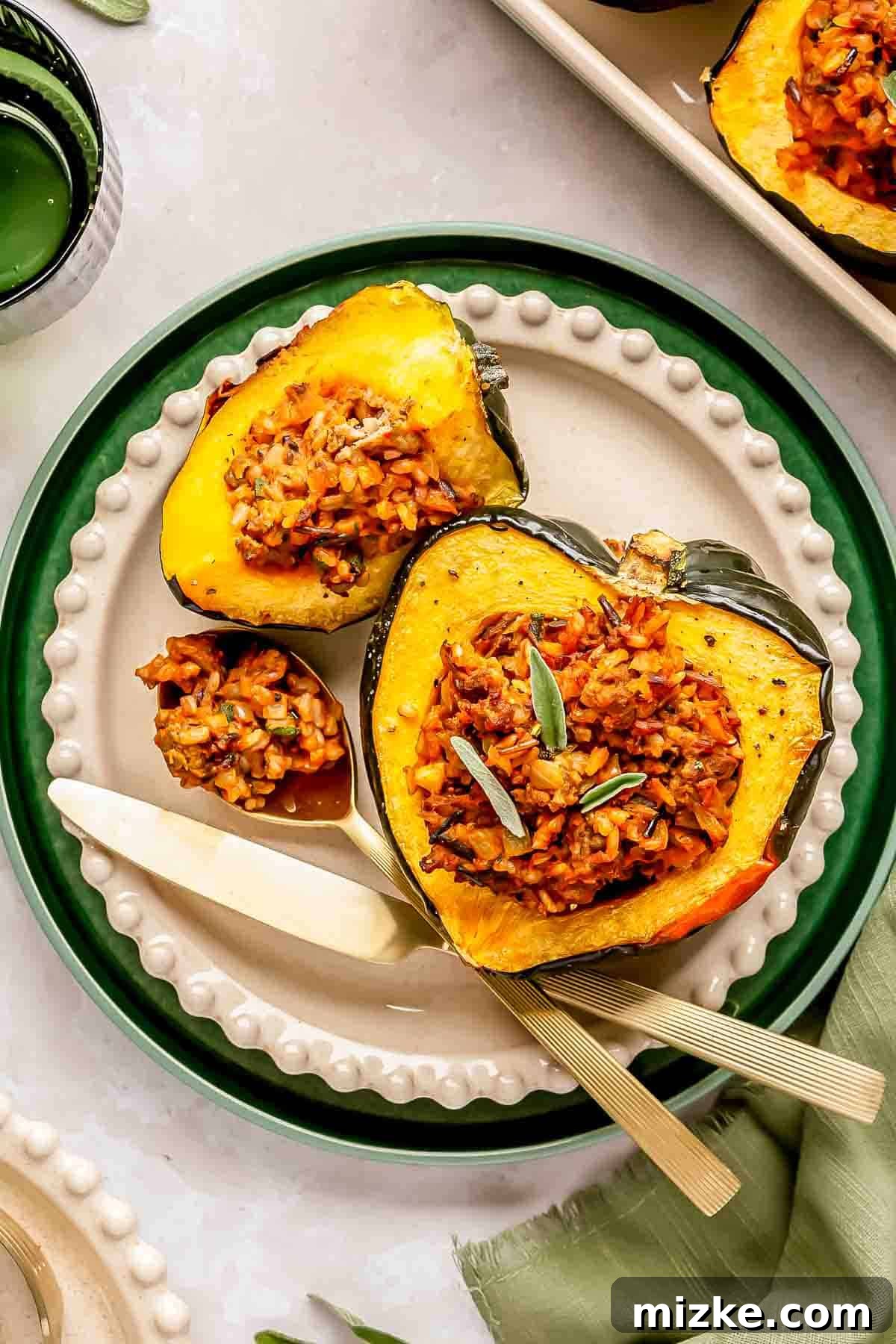 Hearty Stuffed Acorn Squash 2 A plate with beautifully stuffed acorn squash, brimming with a flavorful wild rice and herb mixture. A knife and fork are elegantly placed beside the squash, ready for enjoyment.