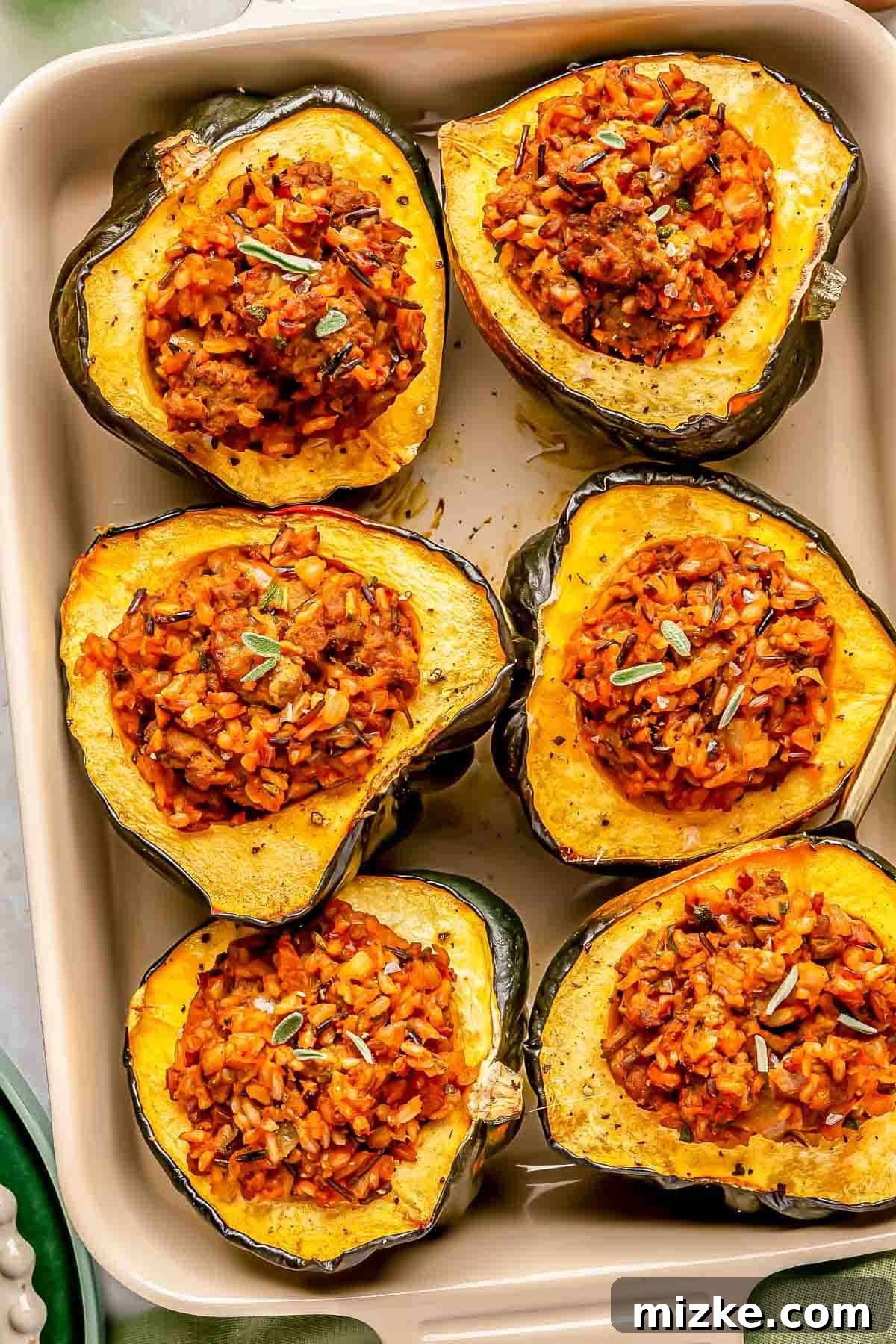 Hearty Stuffed Acorn Squash 3 Six beautifully halved and stuffed acorn squashes, each filled with a seasoned wild rice and herb mixture, artfully arranged in a rectangular baking dish, ready for serving.