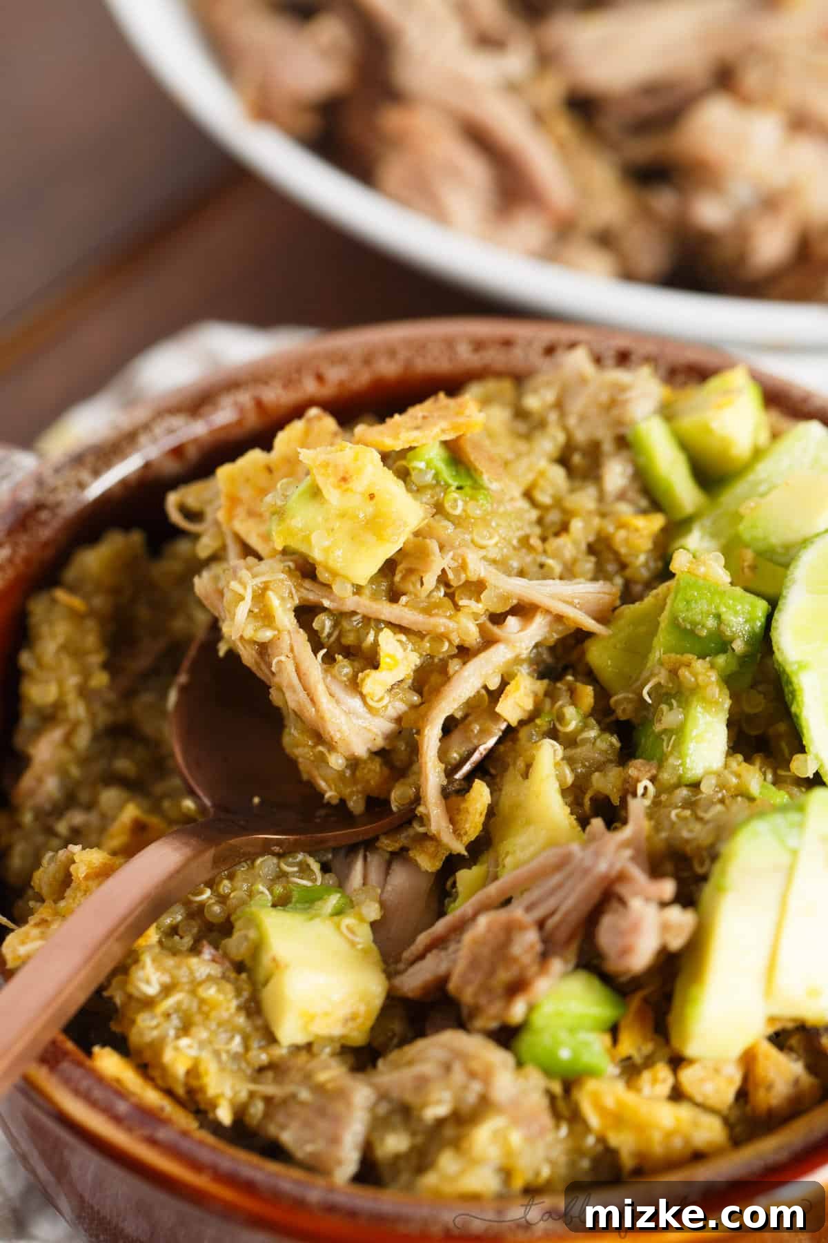 Zesty Slow Cooker Poblano Tomatillo Shredded Pork with Quinoa 6 A close-up shot focusing on the rich, green sauce coating the succulent shredded pork. The steam rising gently suggests a freshly cooked, warm, and inviting meal, emphasizing the depth of flavor in the poblano and tomatillo blend, ready to be served.