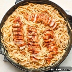 Fiery Cajun Chicken Alfredo 7 sliced chicken tenderloins on top of pasta in a cast iron skillet