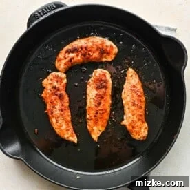 Fiery Cajun Chicken Alfredo 3 chicken tenderloins being browned and cooked in a cast iron skillet