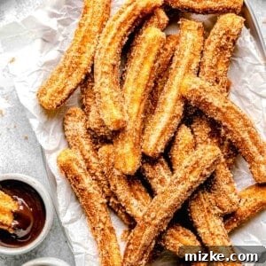 mexican churros on a metal platter next to dipping sauces