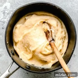 churro dough in a nonstick pot with a wooden spoon