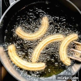 fried churro dough in a cast iron pot with hot oil