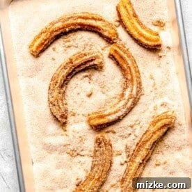 fried churros in cinnamon sugar on a metal baking sheet