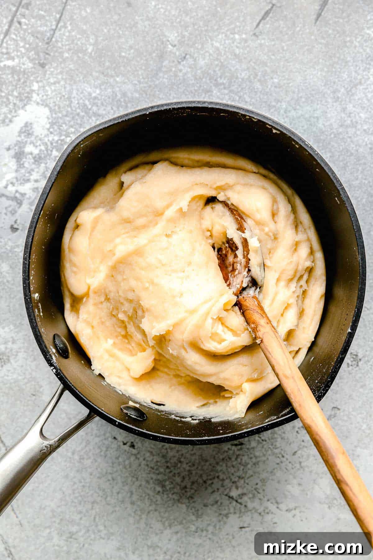 churro dough in a nonstick pot with a wooden spoon