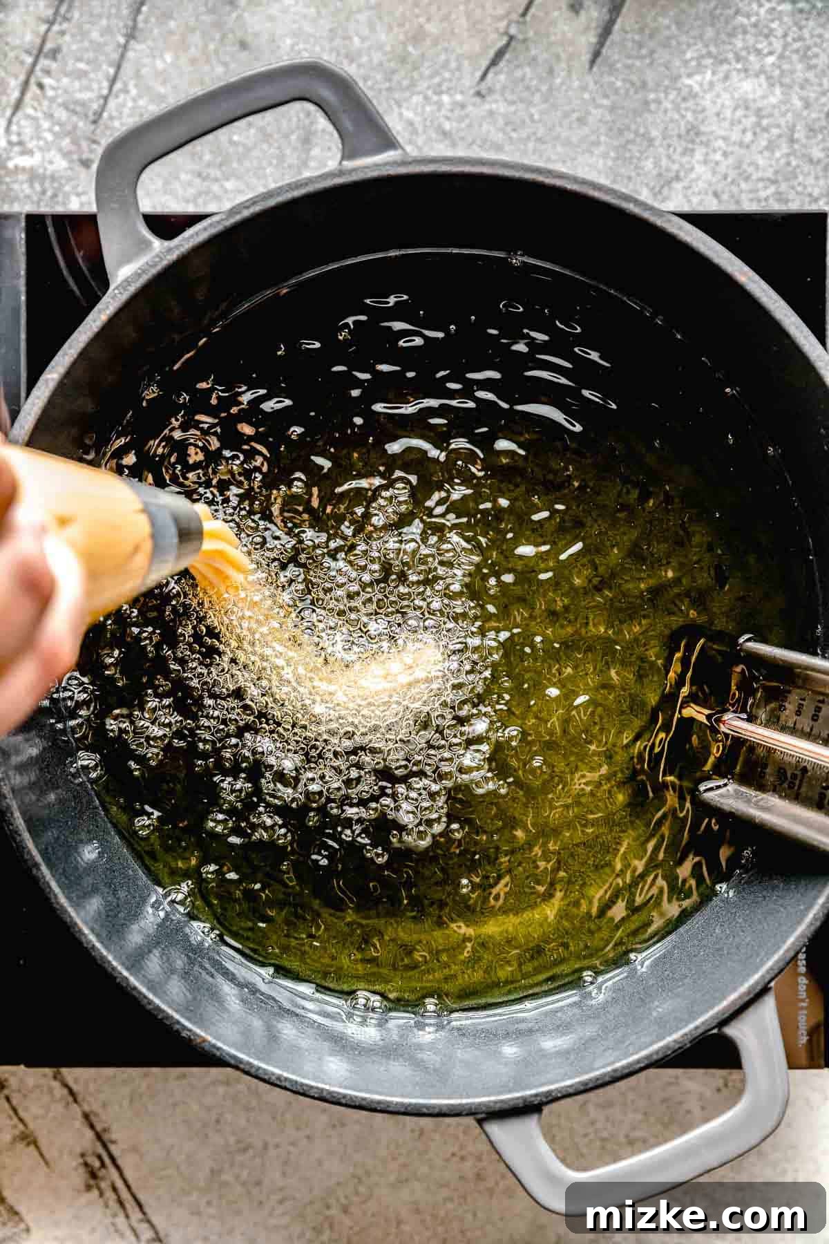 piping churro dough into frying oil on the stovetop
