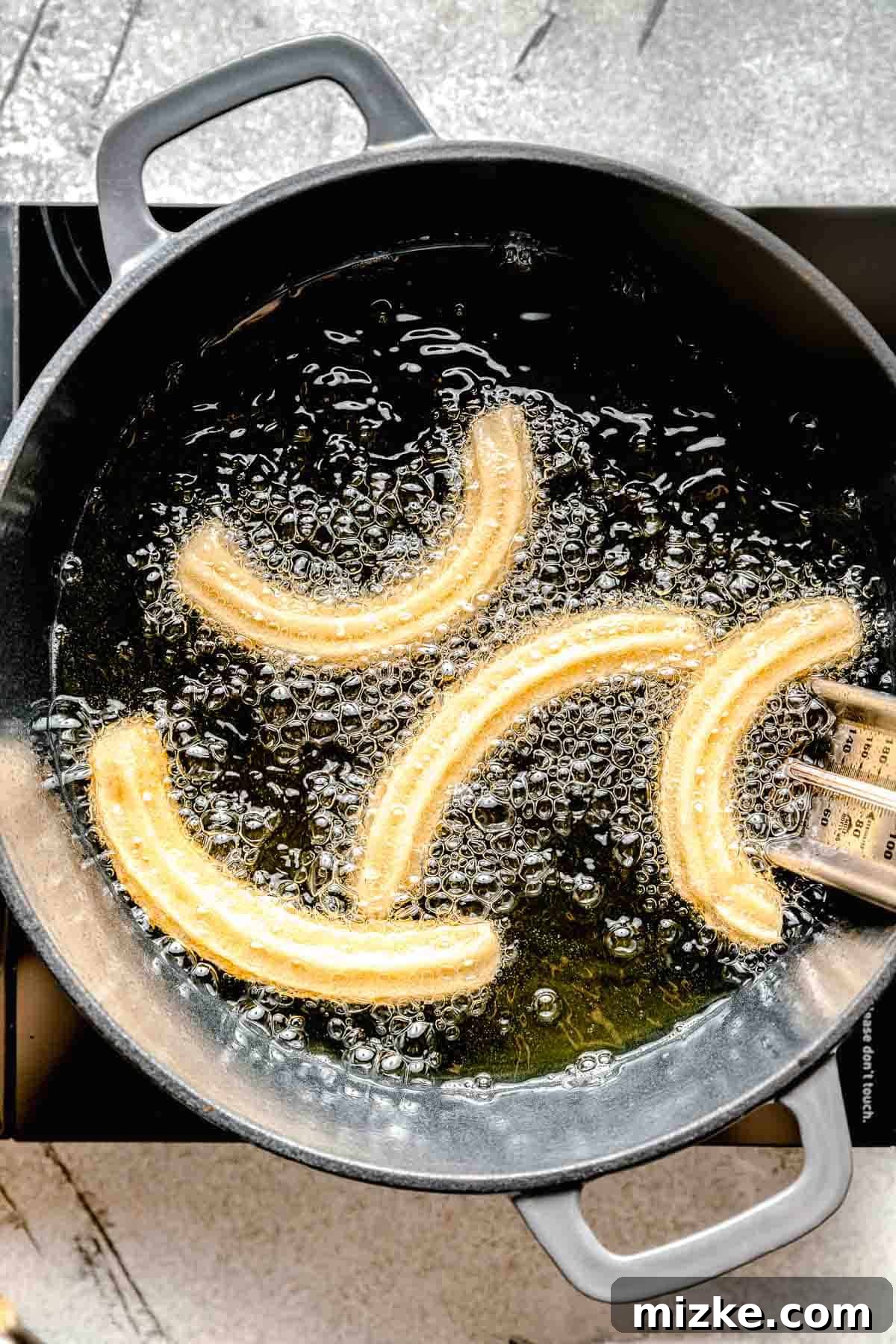 fried churro dough in a cast iron pot with hot oil