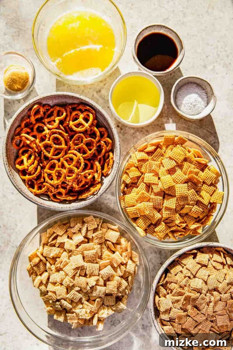 Irresistible Chex Crunch 3 Individual ingredients for homemade Chex Mix laid out on a wooden surface: various Chex cereals, mini pretzels, butter, vegetable oil, Worcestershire sauce, garlic powder, and salt