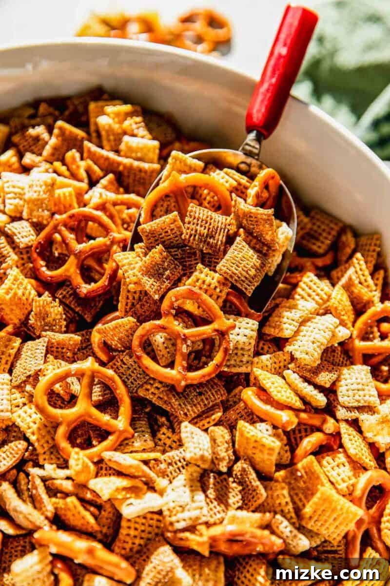 Irresistible Chex Crunch 8 Close-up of homemade Chex Mix being scooped from a large bowl with a red-handled metal scoop
