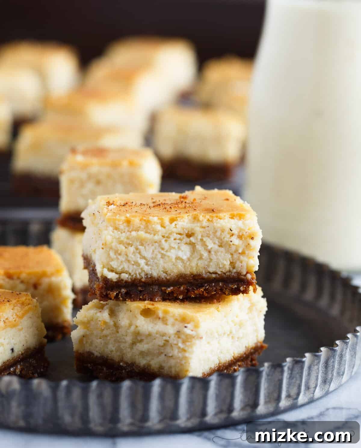 Gingersnap-Crusted Eggnog Cheesecake Bites 5 Overhead view of several eggnog cheesecake bites, ready to be served, dusted with a hint of nutmeg for holiday flavor.