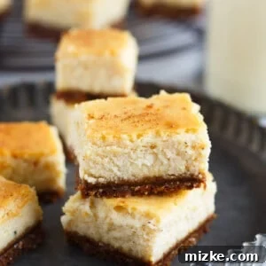 A single, perfectly portioned eggnog cheesecake bite, featuring the intricate layers of creamy eggnog filling and crunchy gingersnap crust, ideal for holiday dessert tables.