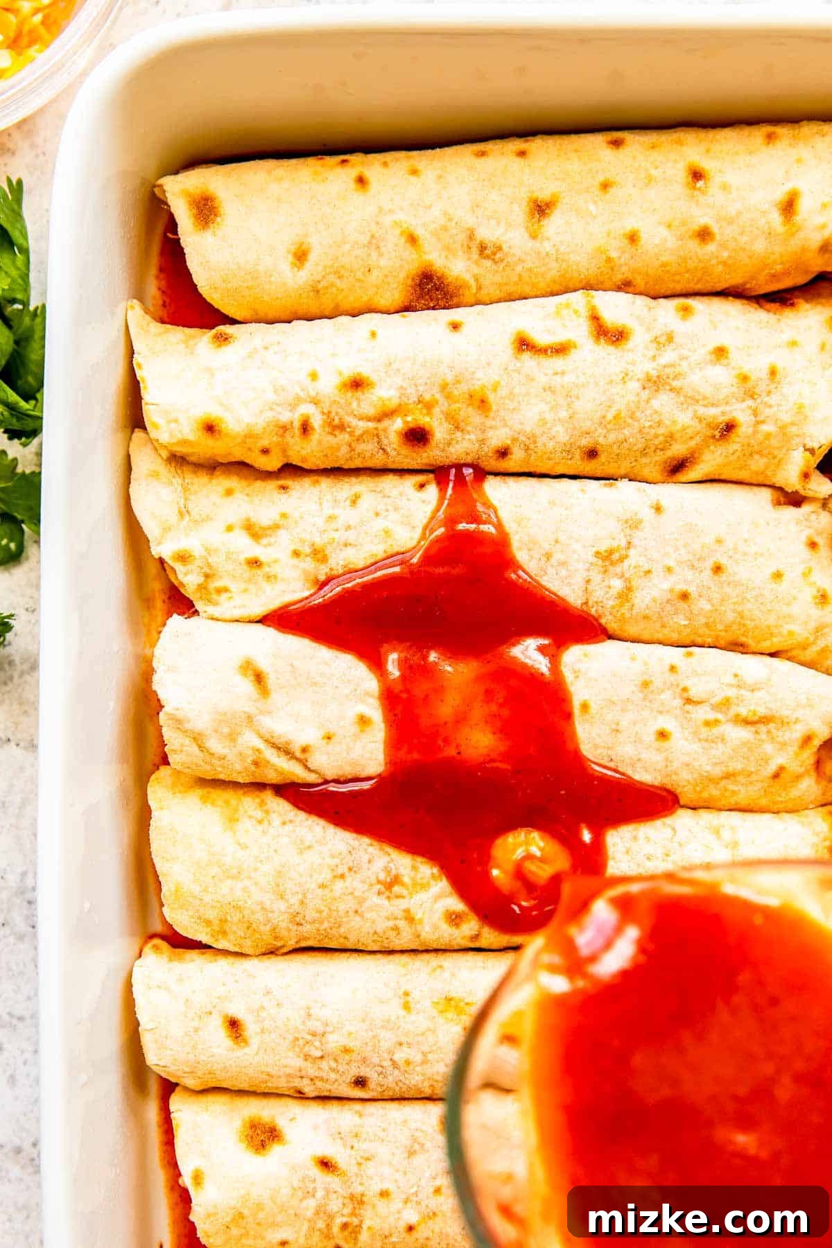 Effortless Homemade Chicken Enchiladas 7 Rich red enchilada sauce is generously poured over the assembled chicken enchiladas in the baking dish, ensuring every roll is coated and flavorful.