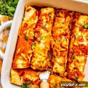 A metal spatula carefully lifting a cheesy chicken enchilada from a white baking dish, showcasing its perfect bake and rich sauce.