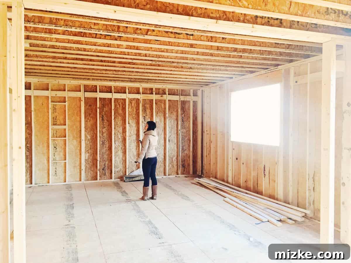 A person standing inside the framed kitchen area of the new house, envisioning the space