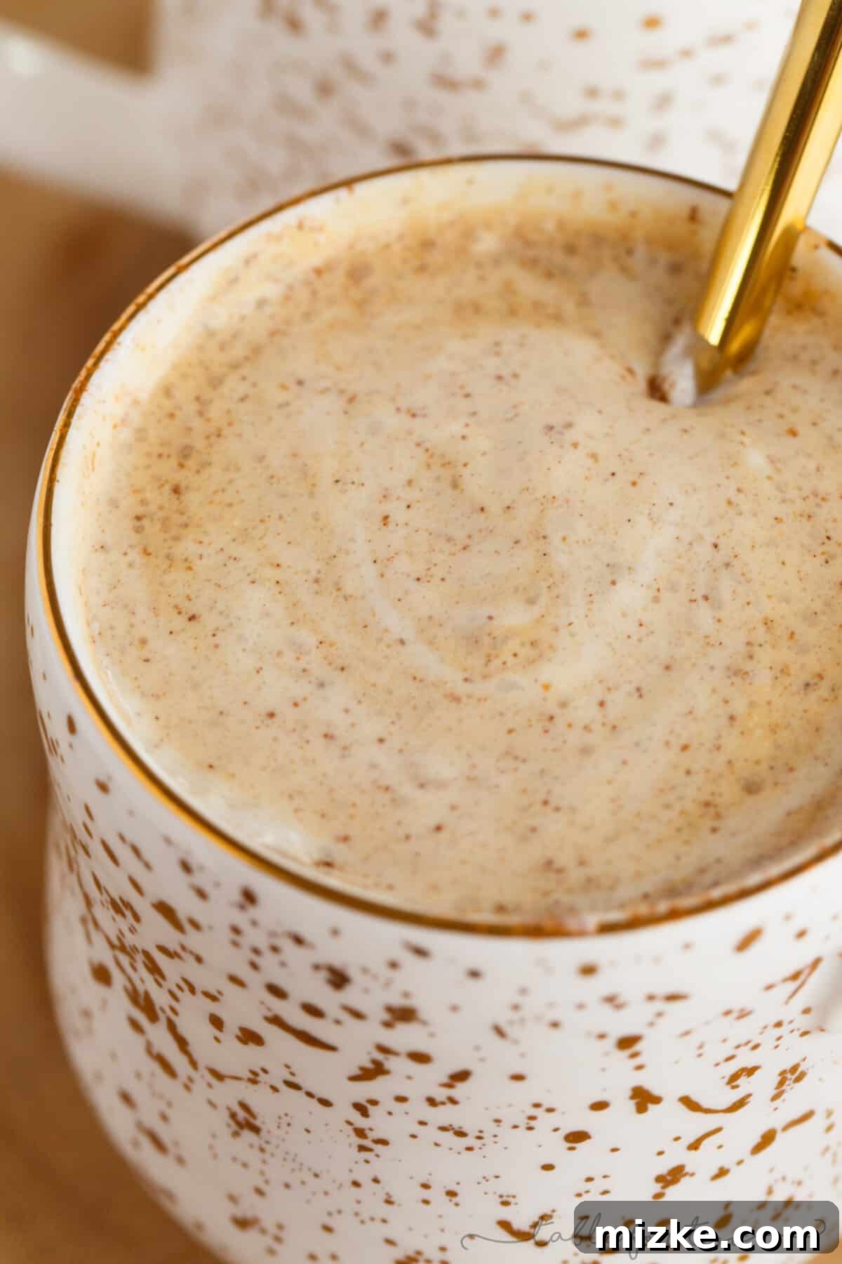 Gingerbread Latte Wonders 5 A festive setting with a spicy gingerbread latte in an elegant gold-speckled mug, accompanied by a small plate of gingersnap cookies, emphasizing holiday cheer.