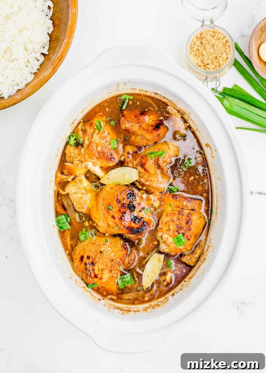 finished chicken adobo in the insert of the slow cooker with fresh scallions sprinkled on top