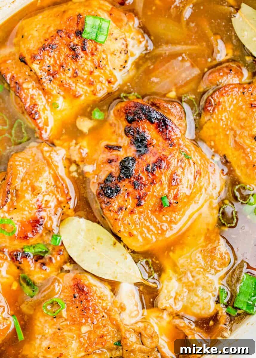 chicken adobo with charred skin in liquid in the insert of a slow cooker