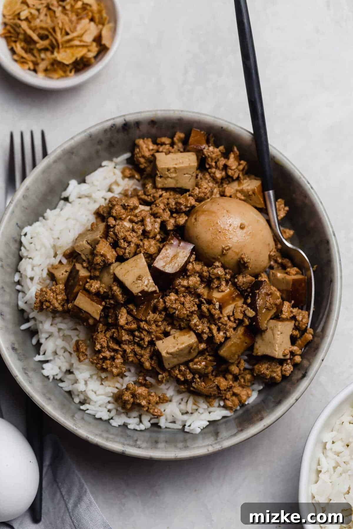 Authentic Taiwanese Braised Minced Pork (Lu Rou Fan) with juicy ground pork, shiitake mushrooms, and eggs – a true Taiwanese comfort food. A beautifully presented bowl of Taiwanese Braised Minced Pork (Lu Rou Fan) served over steaming white rice, garnished with a halved hard-boiled egg and green onions.