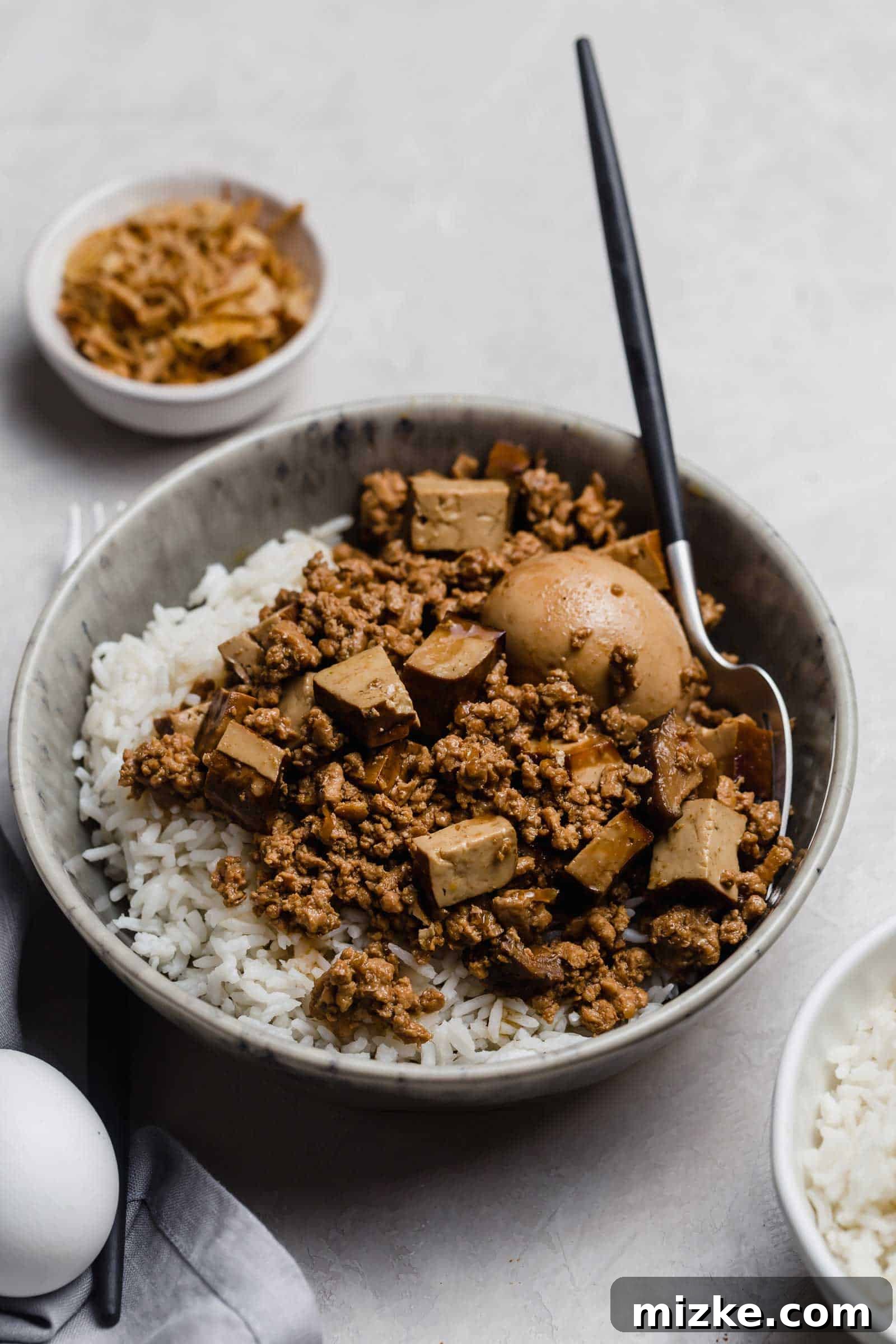 Classic Taiwanese comfort food: Braised minced pork over rice with tofu, egg, and mushrooms. A comforting bowl of white rice generously topped with Taiwanese Braised Minced Pork (Lu Rou Fan), featuring tender pork, savory tofu, earthy mushrooms, and a perfectly braised hard-boiled egg.