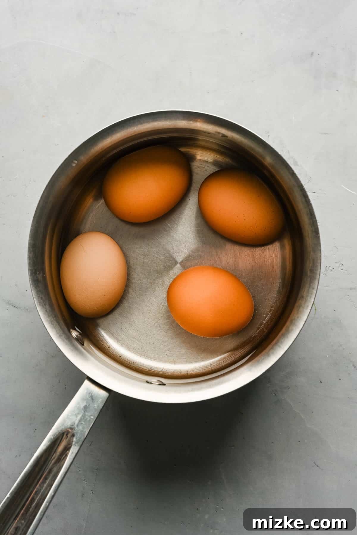 Boiling eggs for Ro Zao – an essential step in preparing Taiwanese braised minced pork. Four eggs boiling in a small stainless steel saucepan on a stovetop, preparing them for the braised pork dish.