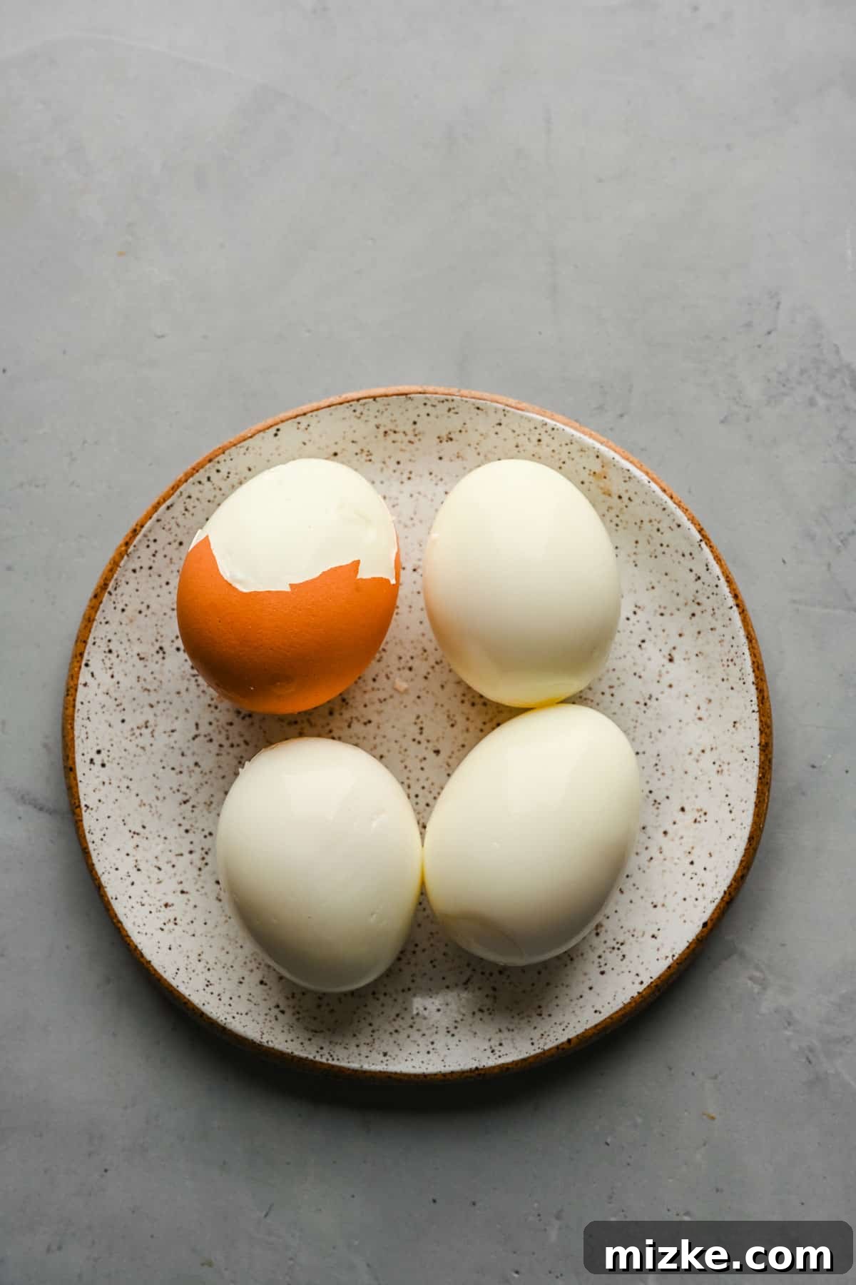 Peeled hard-boiled eggs, ready to be added to the Taiwanese braised minced pork. Several hard-boiled eggs, partially peeled, resting on a white plate, showing their smooth, cooked whites.