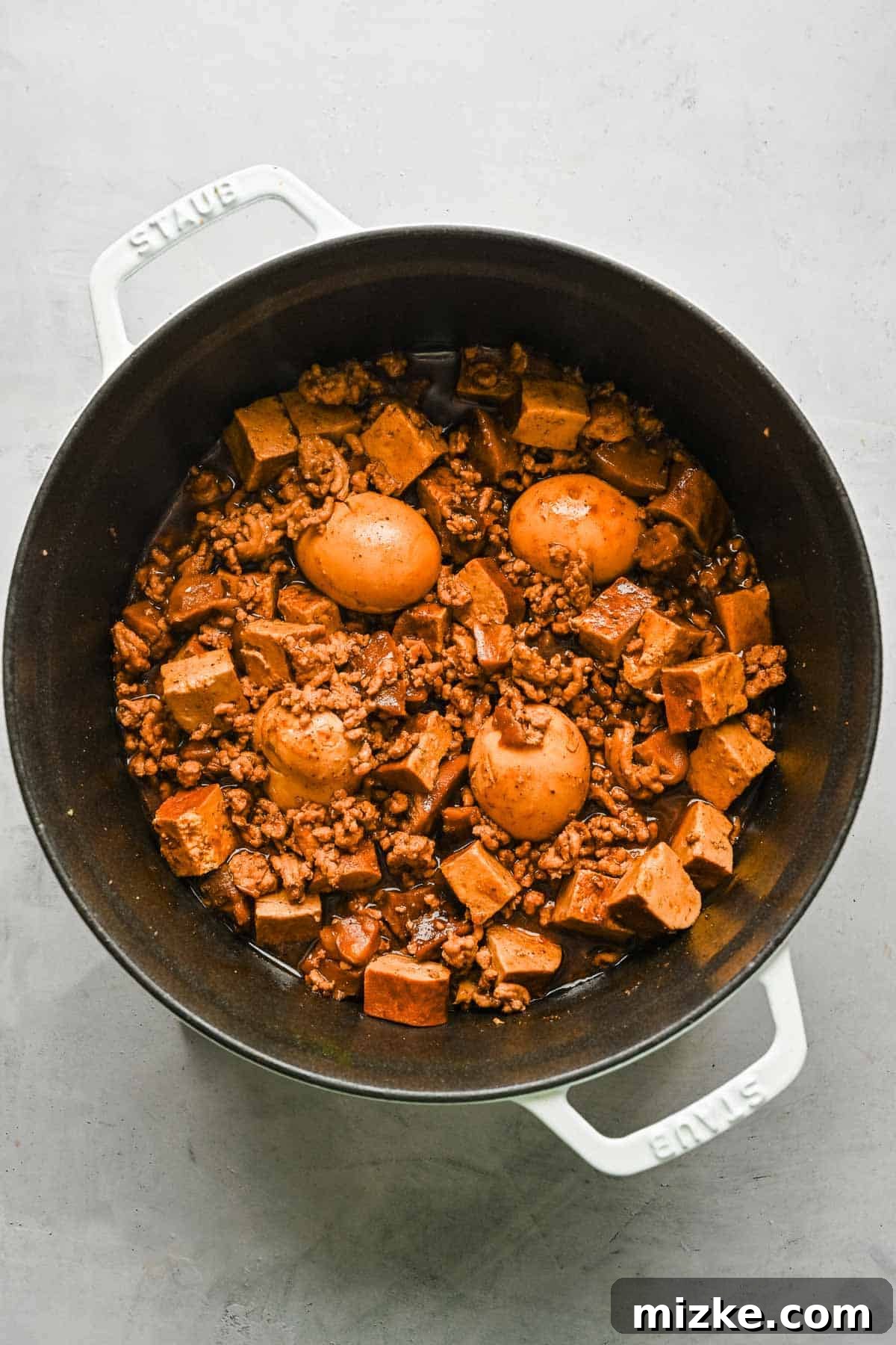 Taiwanese braised minced pork simmering with eggs, mushrooms, and tofu. An overhead view of the braising pot filled with rich Taiwanese minced pork, perfectly mixed with shiitake mushrooms, tofu, and several whole hard-boiled eggs nestled within the savory liquid.