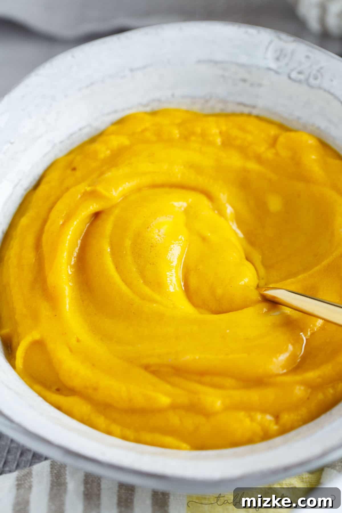 Golden Root Harmony Soup 4 Overhead shot of a vibrant bowl of sweet potato, parsnip, ginger, and turmeric soup, beautifully garnished with a dollop of mascarpone and a sprig of fresh thyme, ready to serve.