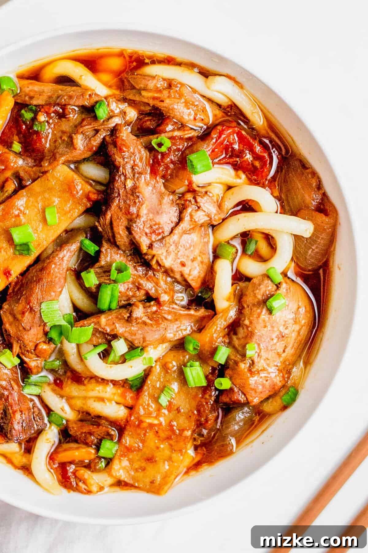 This Instant Pot Taiwanese Beef Noodle Soup offers authentic flavors with modern convenience. Overhead view of a single bowl of Taiwanese beef noodle soup, garnished with vibrant green onions, ready to be enjoyed