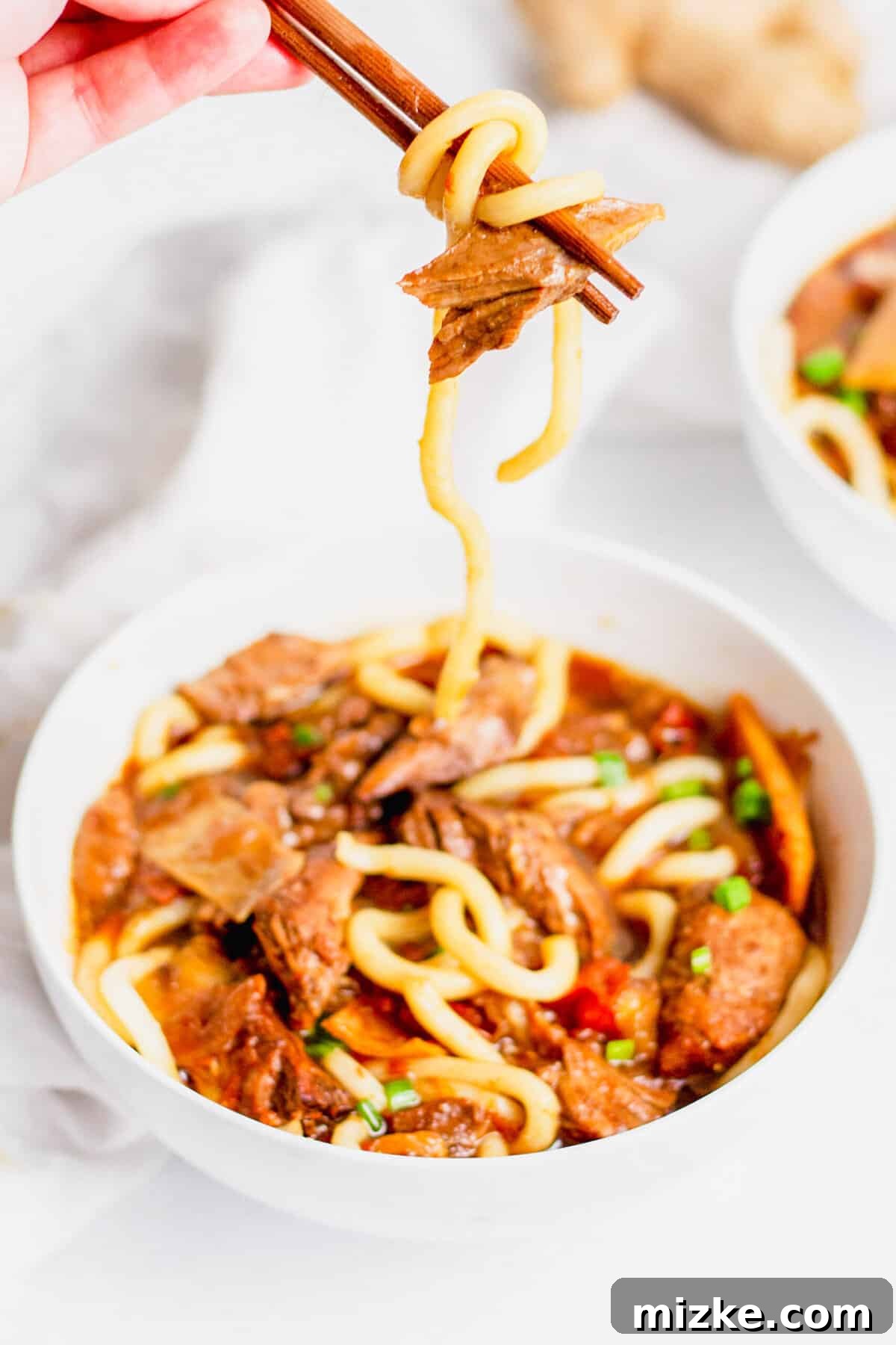 Enjoy customizable Instant Pot Taiwanese Beef Noodle Soup with your preferred noodle and spice levels. Close-up of Taiwanese Beef Noodle Soup, with chopsticks lifting tender beef and noodles from a white bowl