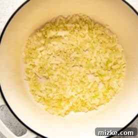 Diced onions and minced garlic sautéing in melted butter in a Dutch oven.
