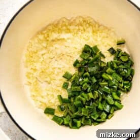 Chopped poblano peppers added to the sautéed onion and garlic mixture in a Dutch oven.