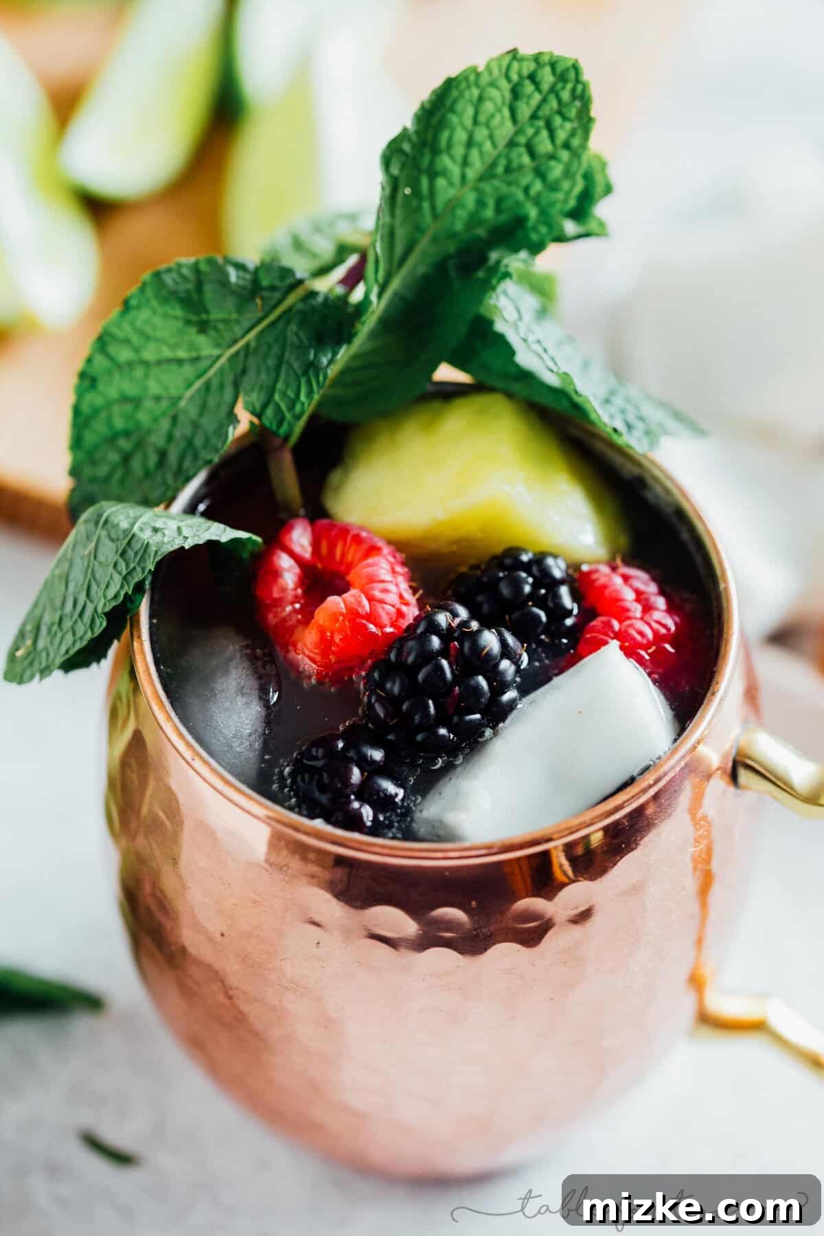 Caribbean Mule 3 Two glistening copper mugs showcasing the Tropical Moscow Mule, garnished with lush mint leaves and colorful pineapple slices, promising a refreshing escape.