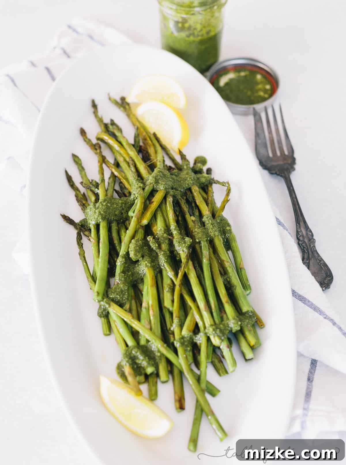 Lemon Kissed Pesto Roasted Asparagus 2 Freshly roasted asparagus spears drizzled generously with homemade lemony pesto, presented as a vibrant and appealing side dish.