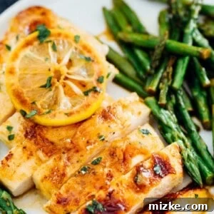 A top-down view of the prepared Honey Butter Lemon Chicken with asparagus in a cast iron skillet.